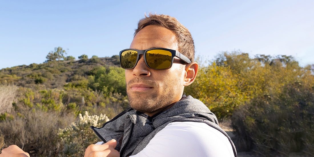 A close up image of a man wearing the Gold Punch Blenders Sunglasses, showcasing a front view and left side view of the matte black to crystal tan fade frame and polarized copper lenses of the sunglasses.