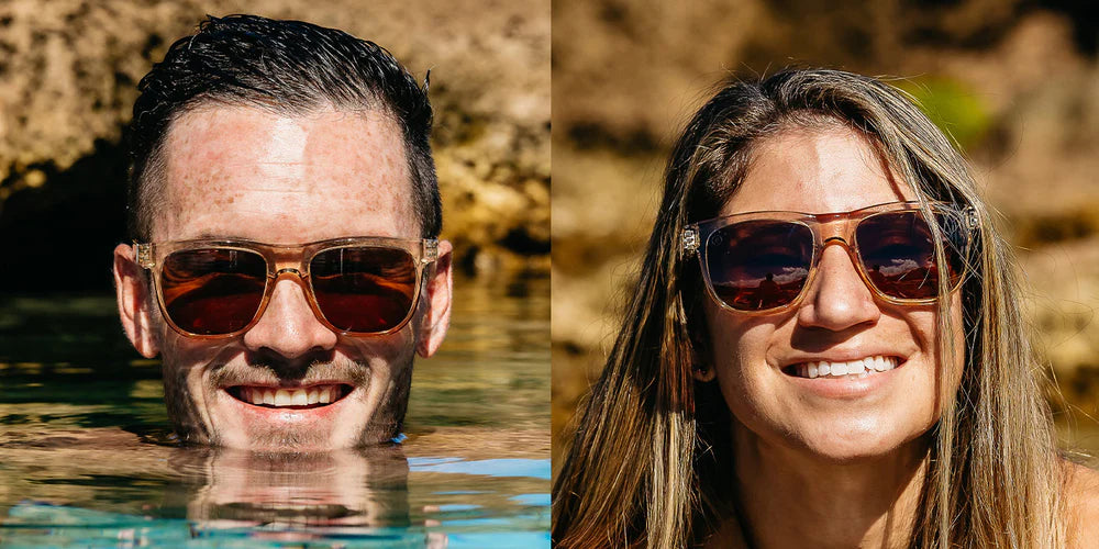 A close up image of a man's and woman's smiling faces wearing the Mojave Cove Blenders Sunglasses, showcasing a front view of the crystal tan and PureBlend™ amber lenses of the sunglasses.