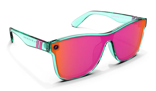 A close up, angled front view of the Dance Electric Blenders Sunglasses showcasing the inside and outside of the gloss crystal teal frame and polarized hot pink mirrored lenses of the sunglasses